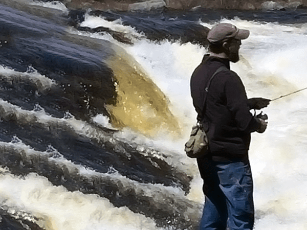 Steve B. fishing by a water rapid in Maine